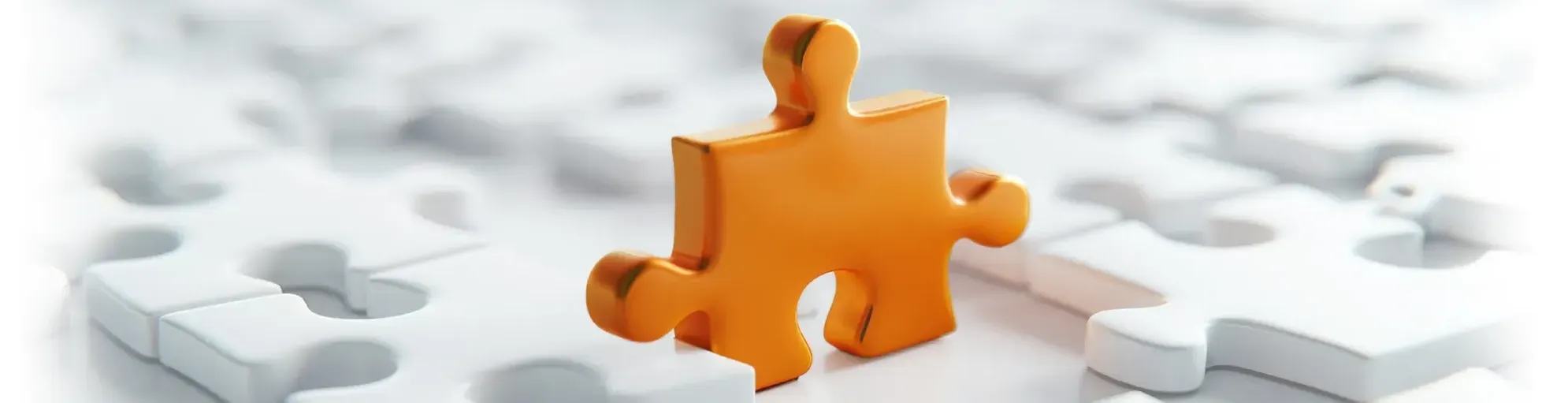 Über uns: ein orangefarbendes Puzzlestück steht inmitten von liegenden weißen Puzzelstücken